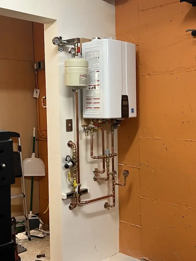 Plumbing technician inspecting water heater connections in Albion